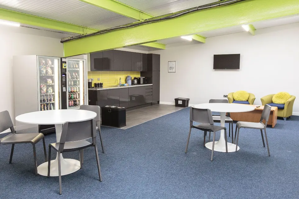Staff room with tables and chairs, kitchen area, and vending machines